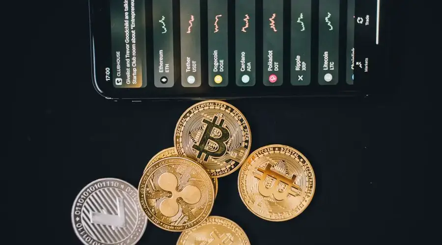Close-up of various cryptocurrencies and a smartphone showing market trends.
