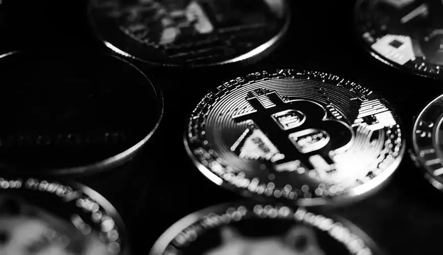 Monochrome close-up shot of Bitcoin and cryptocurrency coins, capturing digital currency essence.