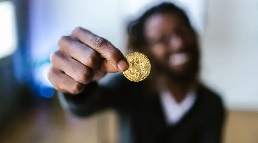 A person holding a Bitcoin coin, representing cryptocurrency and digital finance concepts.