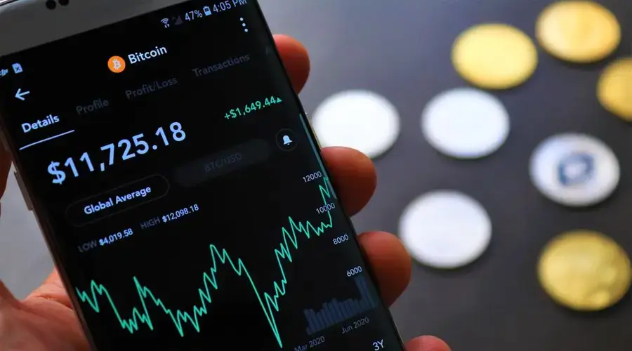 Close-up of Bitcoin trading app on smartphone showing market trends and digital coins.