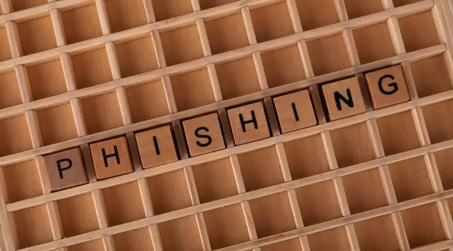 Wooden Scrabble tiles arranged to spell 'Phishing', illustrating online security concepts.