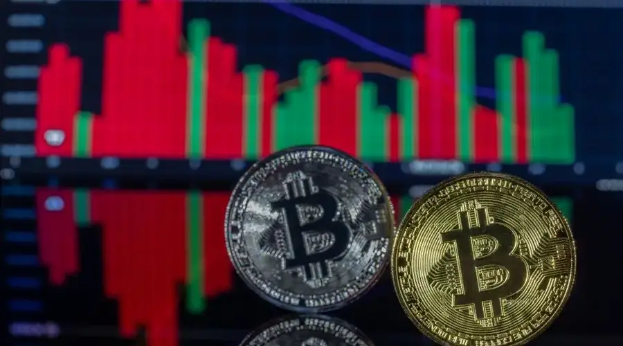 Two Bitcoin coins in front of a financial chart showcasing cryptocurrency trading trends.