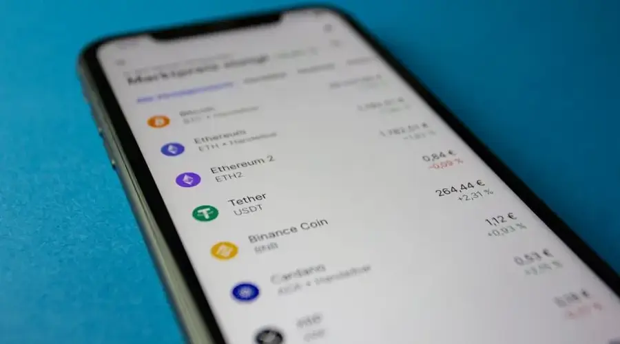Close-up photo of a smartphone displaying cryptocurrency market data with price listings.