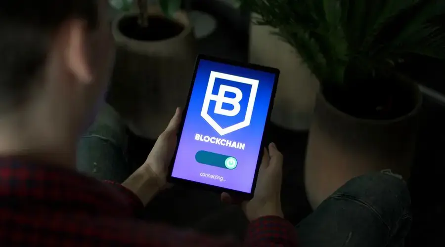 Person holding a digital tablet showing blockchain connection screen indoors.