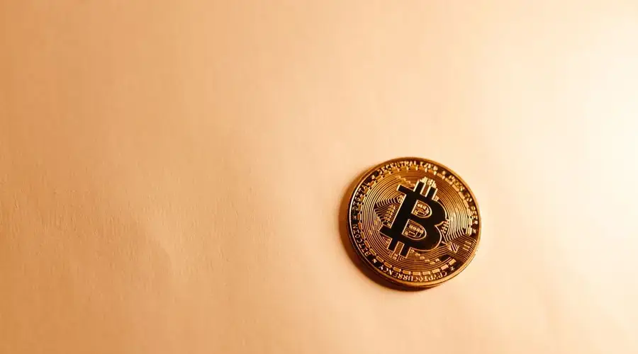 Close-up of a Bitcoin coin on a soft, neutral background representing the digital currency concept.