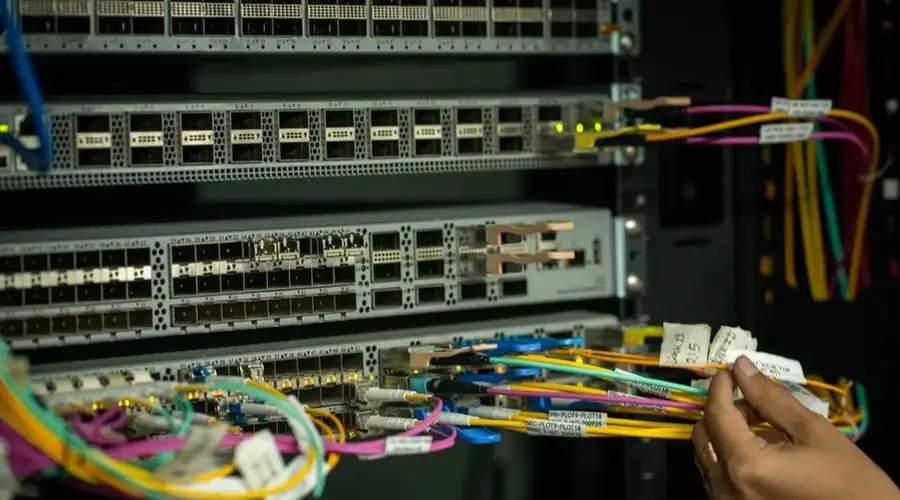 A hand managing fiber optic cables in a server room, showcasing modern connectivity.