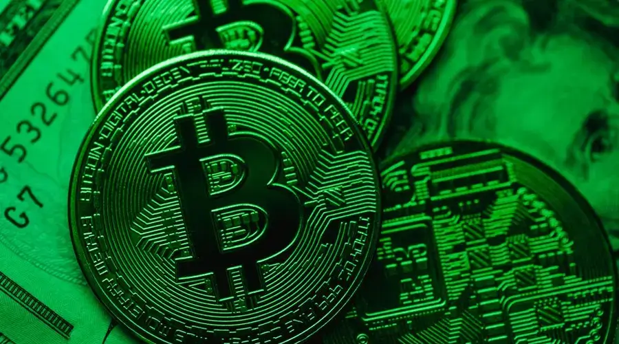 Close-up of Bitcoin coins on paper cash, with a green color tint.