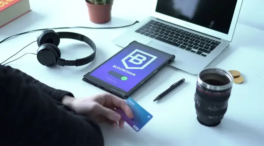 Modern workspace featuring blockchain technology. Laptop, tablet, and card on a desk.