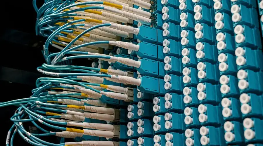 Detailed view of fiber optic patch cables connecting to a blue patch panel in a data center.