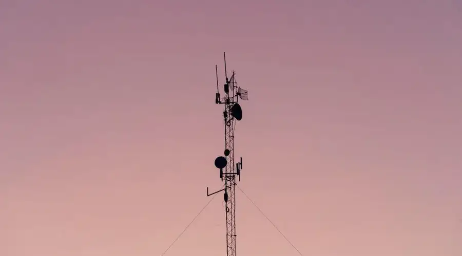 A tall telecommunication tower silhouetted against a clear dusk sky.