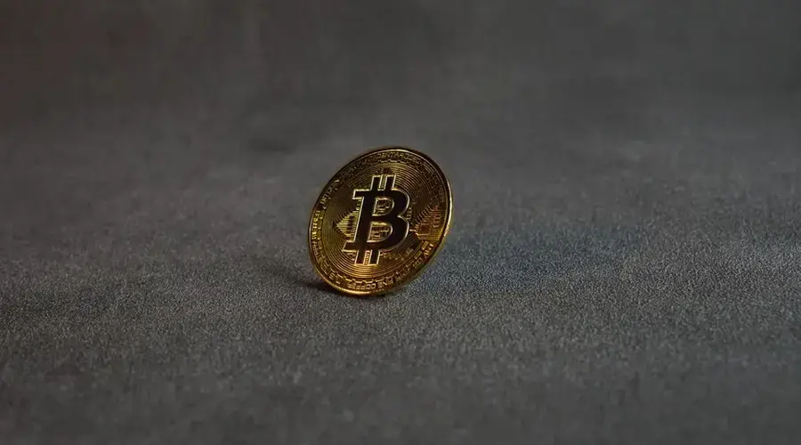 Close-up image of a golden Bitcoin standing on a grey surface, symbolizing cryptocurrency and digital finance.