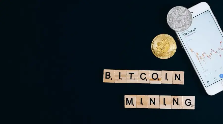 A smartphone displaying cryptocurrency trends alongside Bitcoin coins, suggesting mining.