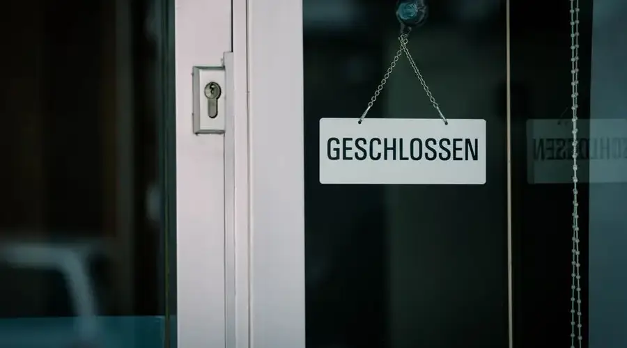 A close-up view of a 'Geschlossen' sign hanging on a door, indicating closure.