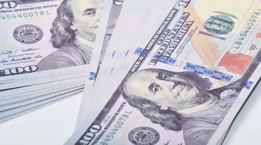 A detailed close-up of stacked US 100 dollar banknotes representing wealth and finance.