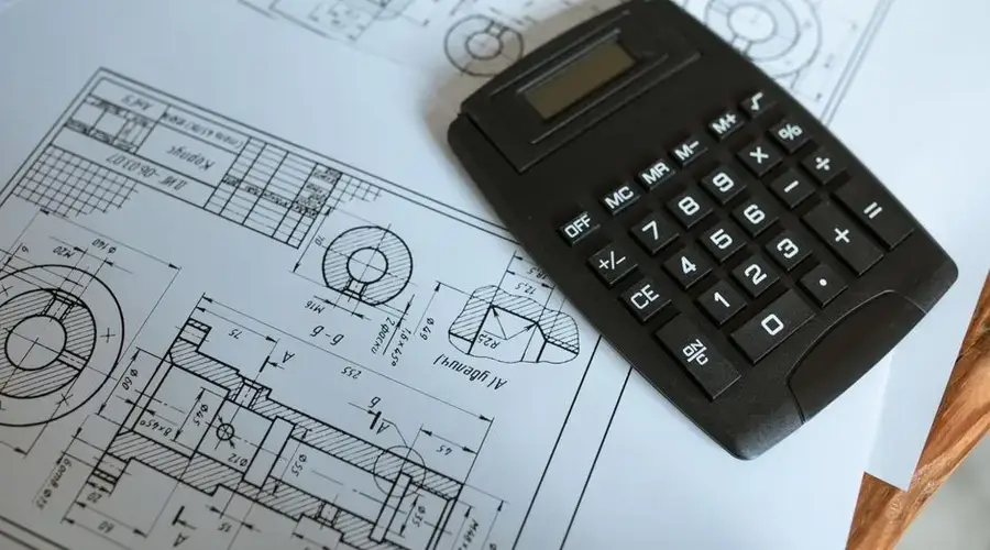 Close-up of a calculator resting on technical engineering blueprints, showcasing precise calculations.