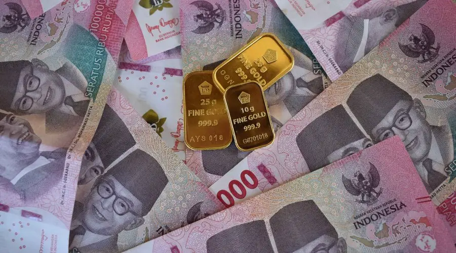 Close-up of Indonesian Rupiah banknotes with fine gold bars, symbolizing wealth and investment.