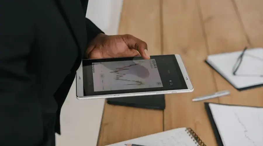 Businessperson reviewing data charts on a tablet device in an office setting.