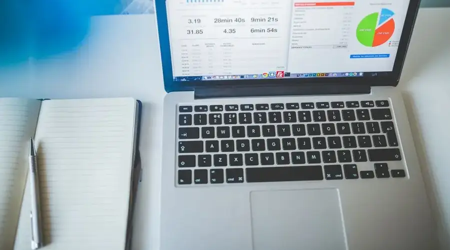 Laptop displaying charts and graphs next to a notebook, ideal for business and tech themes.