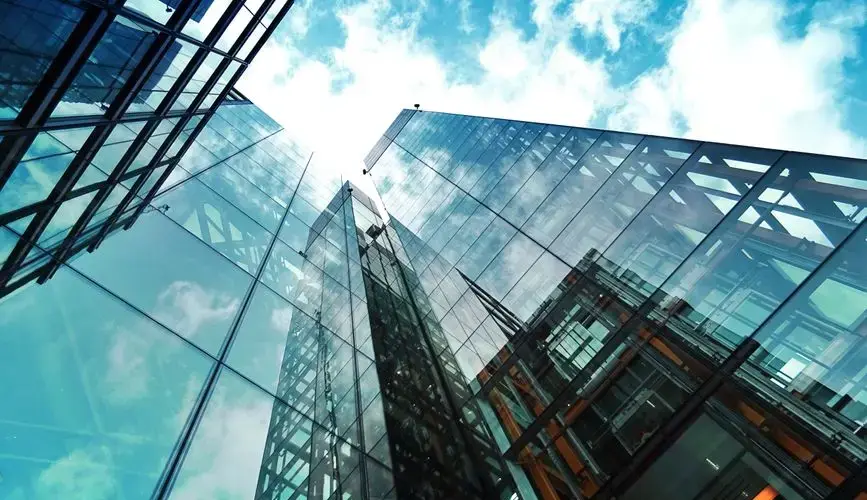 A striking view of a modern glass skyscraper reflecting the sky and clouds.