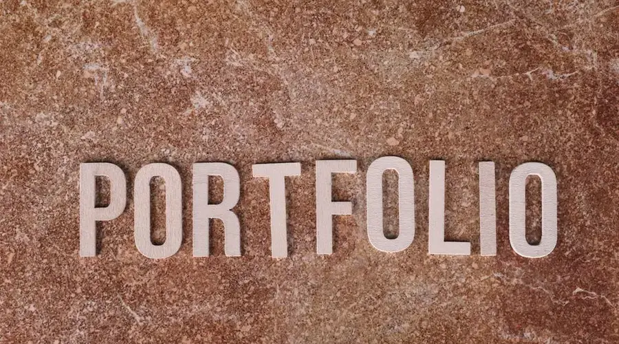 Metallic 'PORTFOLIO' letters on textured brown marble surface. Ideal for presentations.