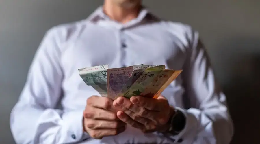 Man holding Argentine Peso banknotes in Buenos Aires, Argentina, illustrating currency concept.