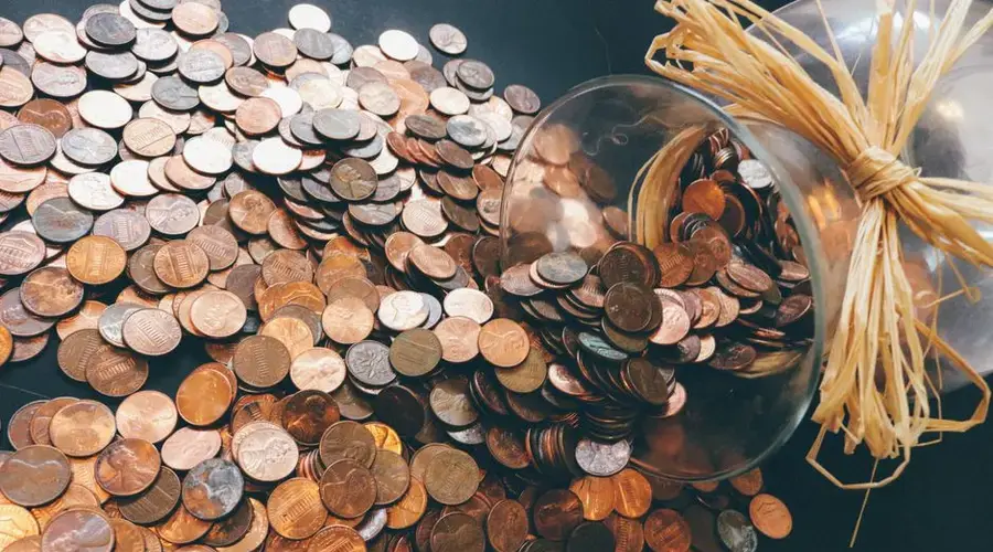 Spilled jar of pennies creating a pattern of coins representing savings and finance.