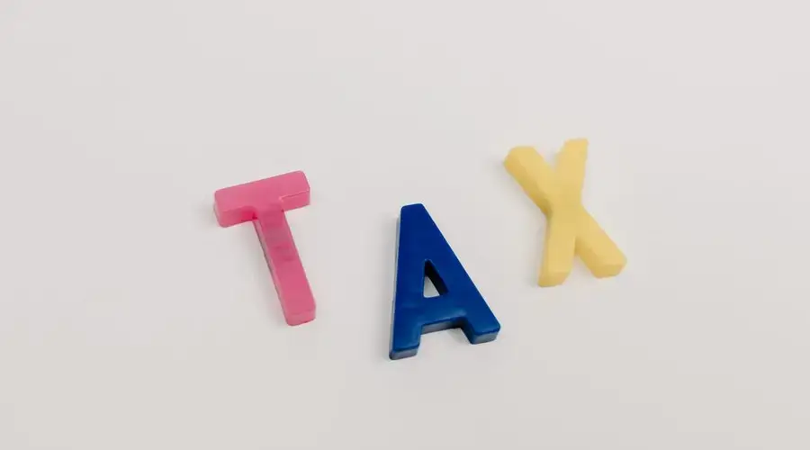 Colorful plastic letters spelling tax on a clean white background.