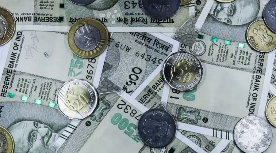 Top view of various Indian rupee banknotes and coins, highlighting financial themes.