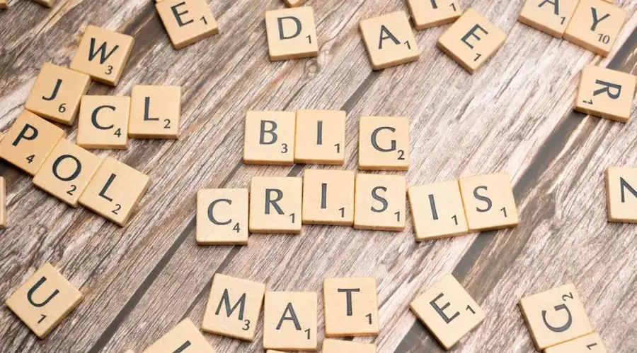 Wooden tiles forming the words 'Big Crisis' on a wooden background.