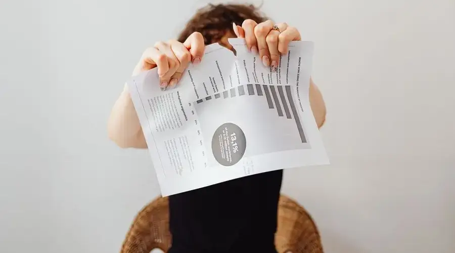 A frustrated individual tearing a printed document with graphs and text.