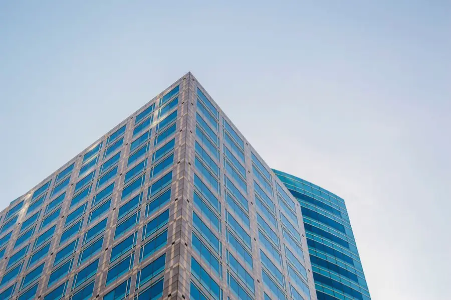 Low angle view of a modern skyscraper with reflective glass windows against a clear sky.