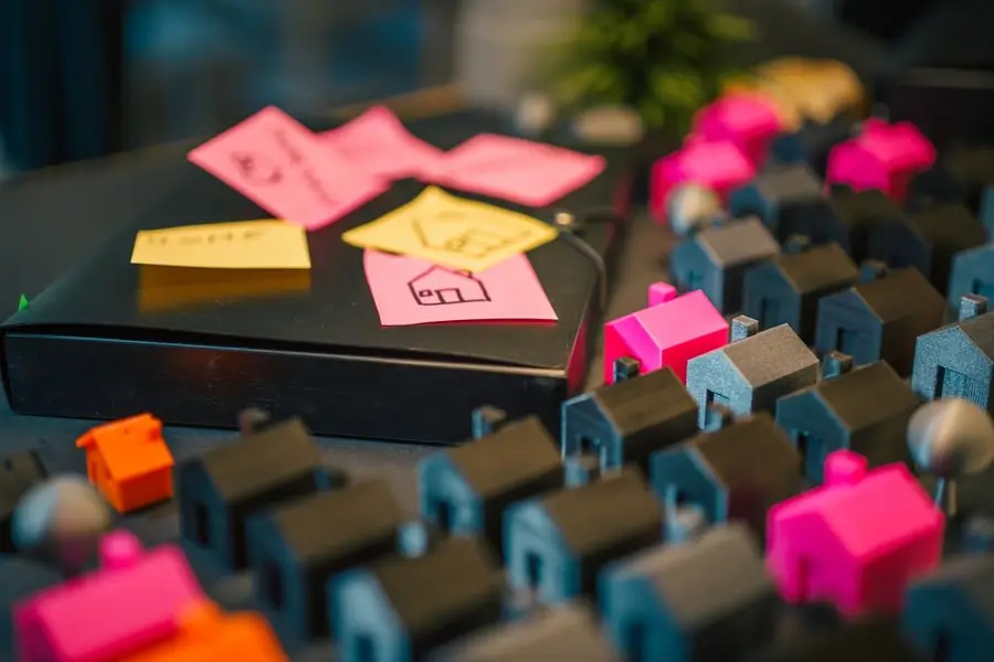 A vibrant display of miniature houses and sticky notes, illustrating real estate planning concepts.