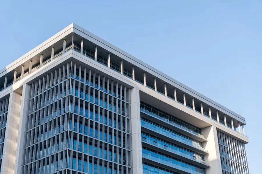 Contemporary highrise building with glass facade under a clear blue sky.