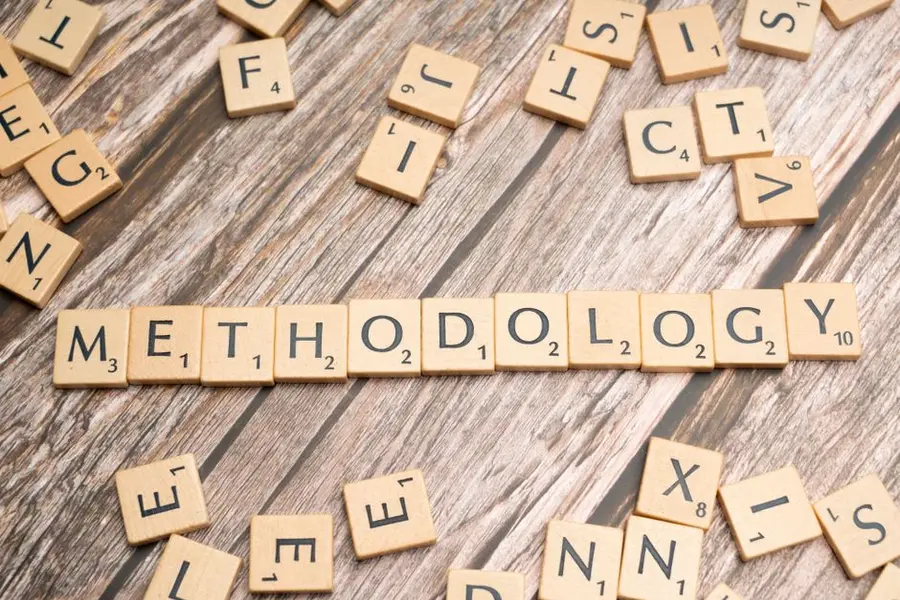 Wooden letter tiles spelling 'methodology' on a textured wooden surface, emphasizing research.