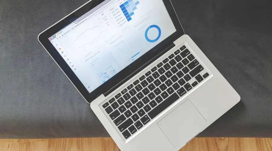 Overhead view of a laptop showing data visualizations and charts on its screen.