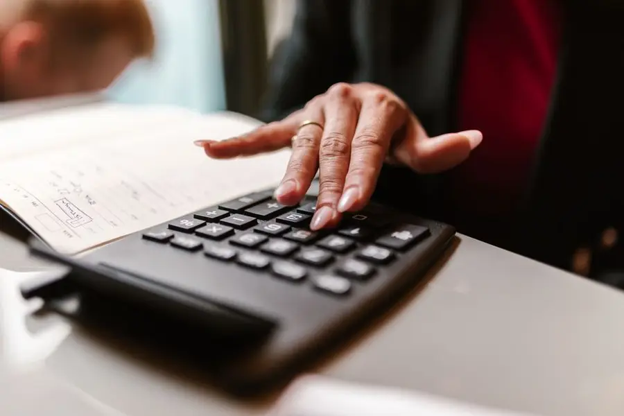 A person's hand using a calculator on a desk, capturing focus and concentration.
