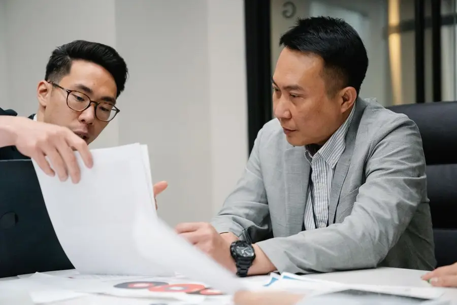 Two professional men engaged in a focused discussion in a contemporary office environment.