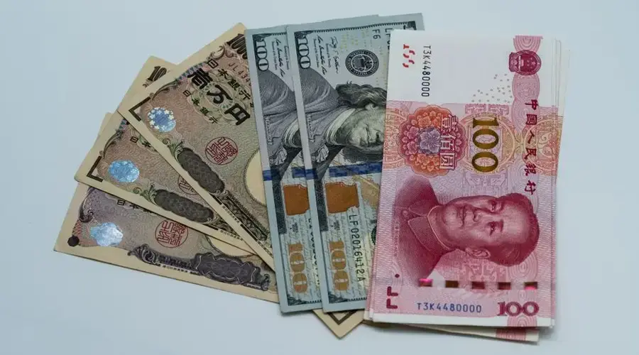 Various international currency notes including US dollars, yen, and yuan arranged on a surface.