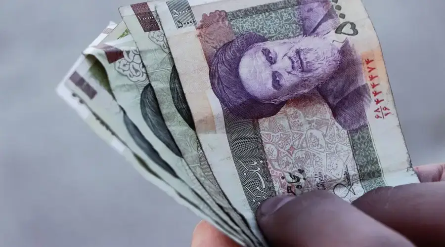 Detailed view of Iranian rial banknotes held in hand, illustrating finance and economy in Iran.