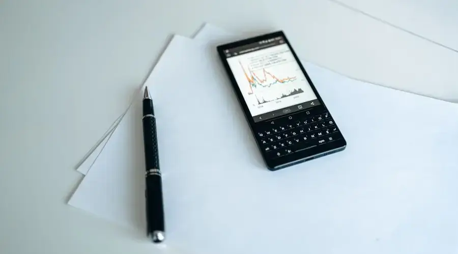 Smartphone displaying graphs on paper with a pen, perfect for business strategy concepts.