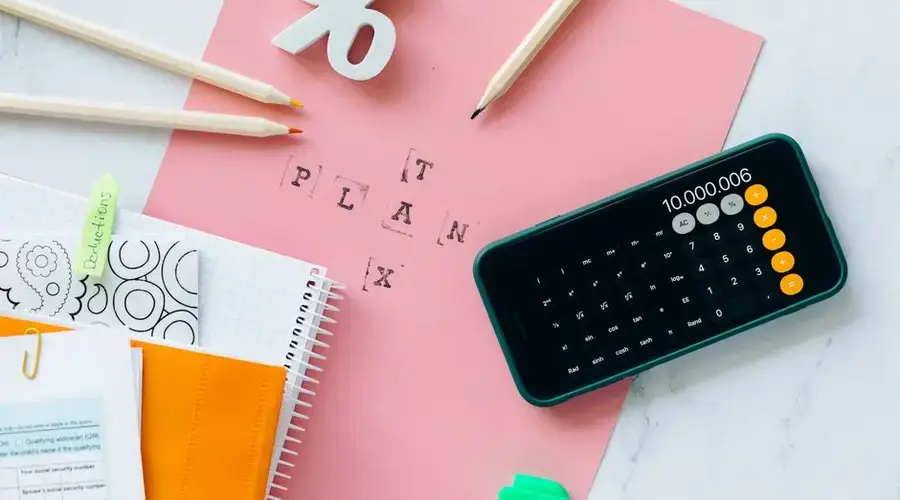 Flat lay showing tax planning tools including a calculator, pencils, and stationery items.