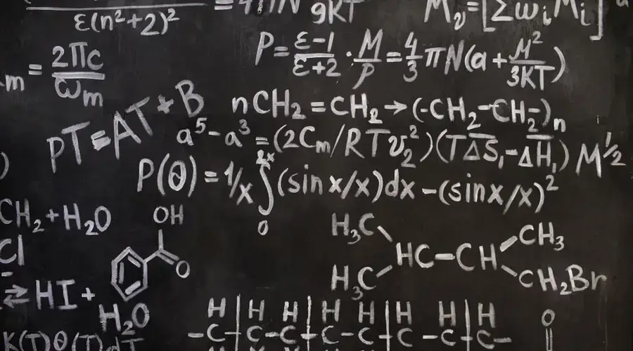 A close-up view of complex mathematical and chemical formulas on a blackboard.
