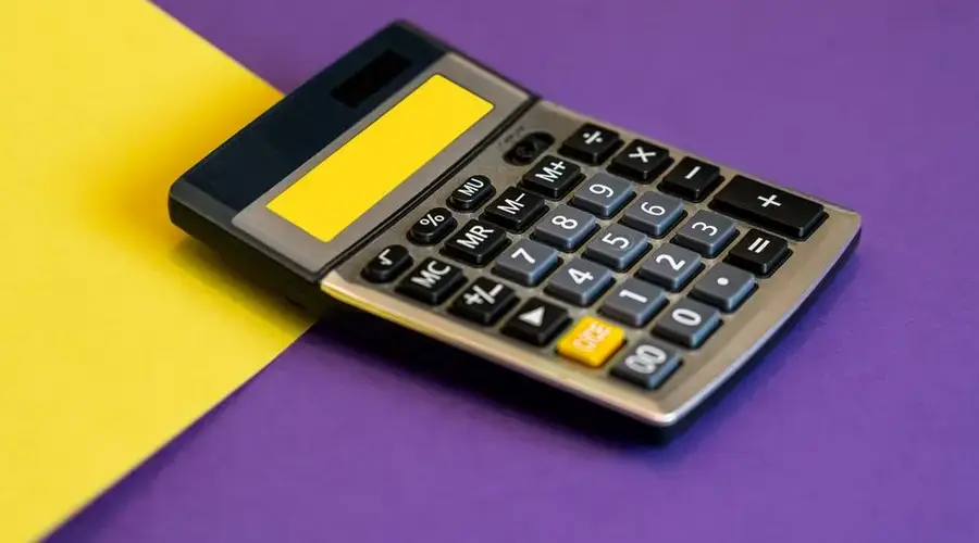 A calculator on vibrant yellow and purple background representing business finance.