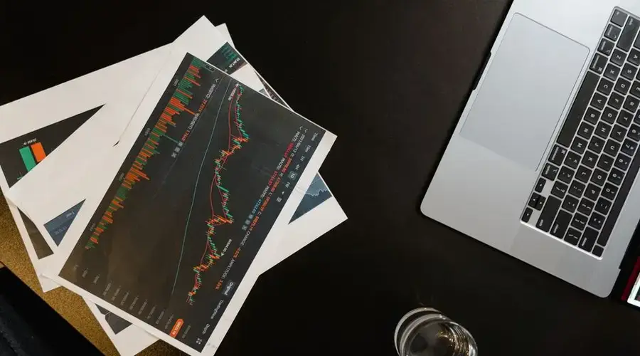 An overhead view of charts and graphs alongside a laptop on a black surface.