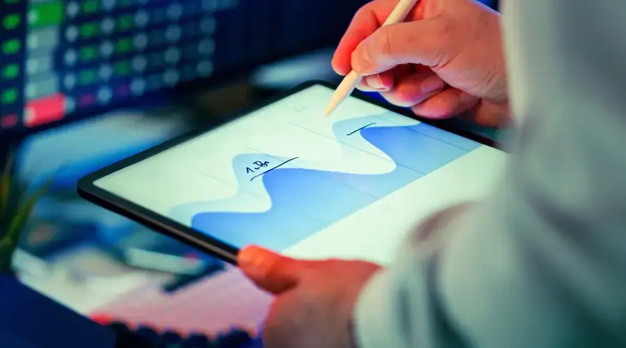 Professional analyzing data chart on a tablet with stylus in an office setting.