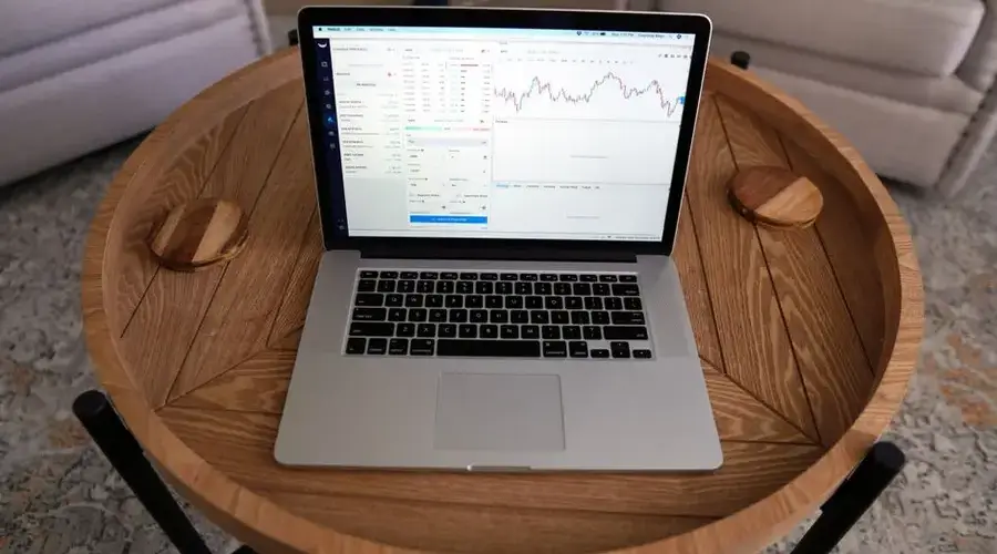 Close-up of a laptop displaying trading charts on a stylish wooden table, ideal for financial themes.