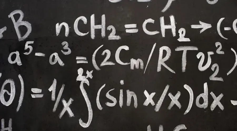 Close-up of complex equations on a chalkboard, showcasing chemistry and math symbols.
