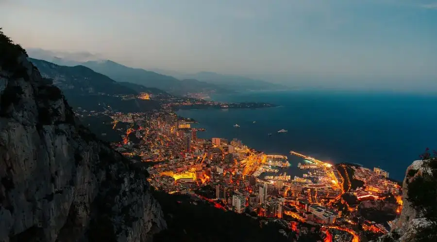 Stunning aerial perspective of Monaco's illuminated harbor and cityscape at twilight.