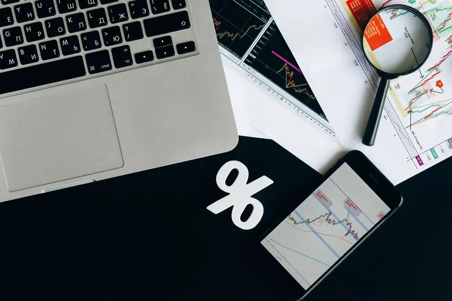 Overhead view of financial analysis tools with laptop, smartphone, and charts on a desk.