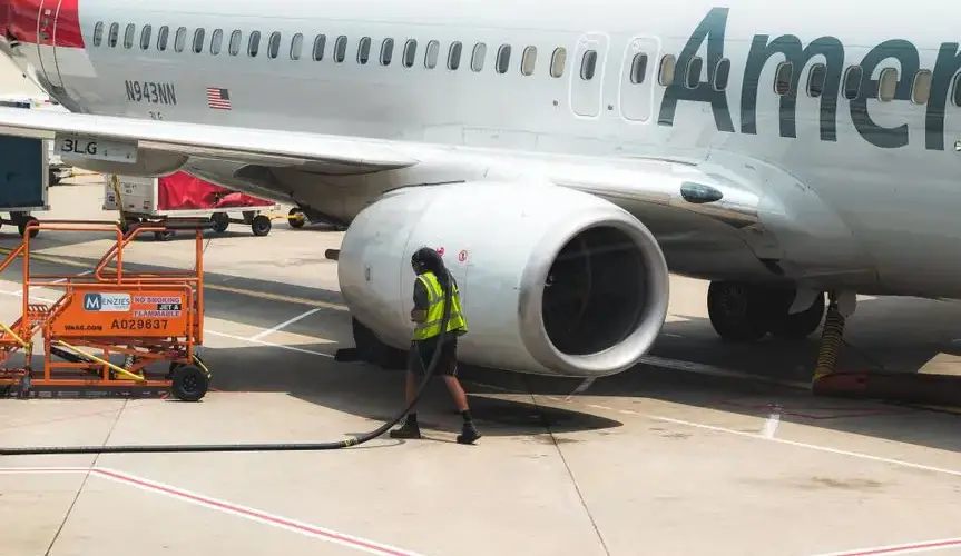 A worker services a commercial airplane on the runway in Las Vegas.